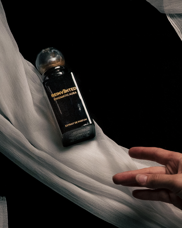 Perfume bottle labeled 'Reinvented' on a white fabric background