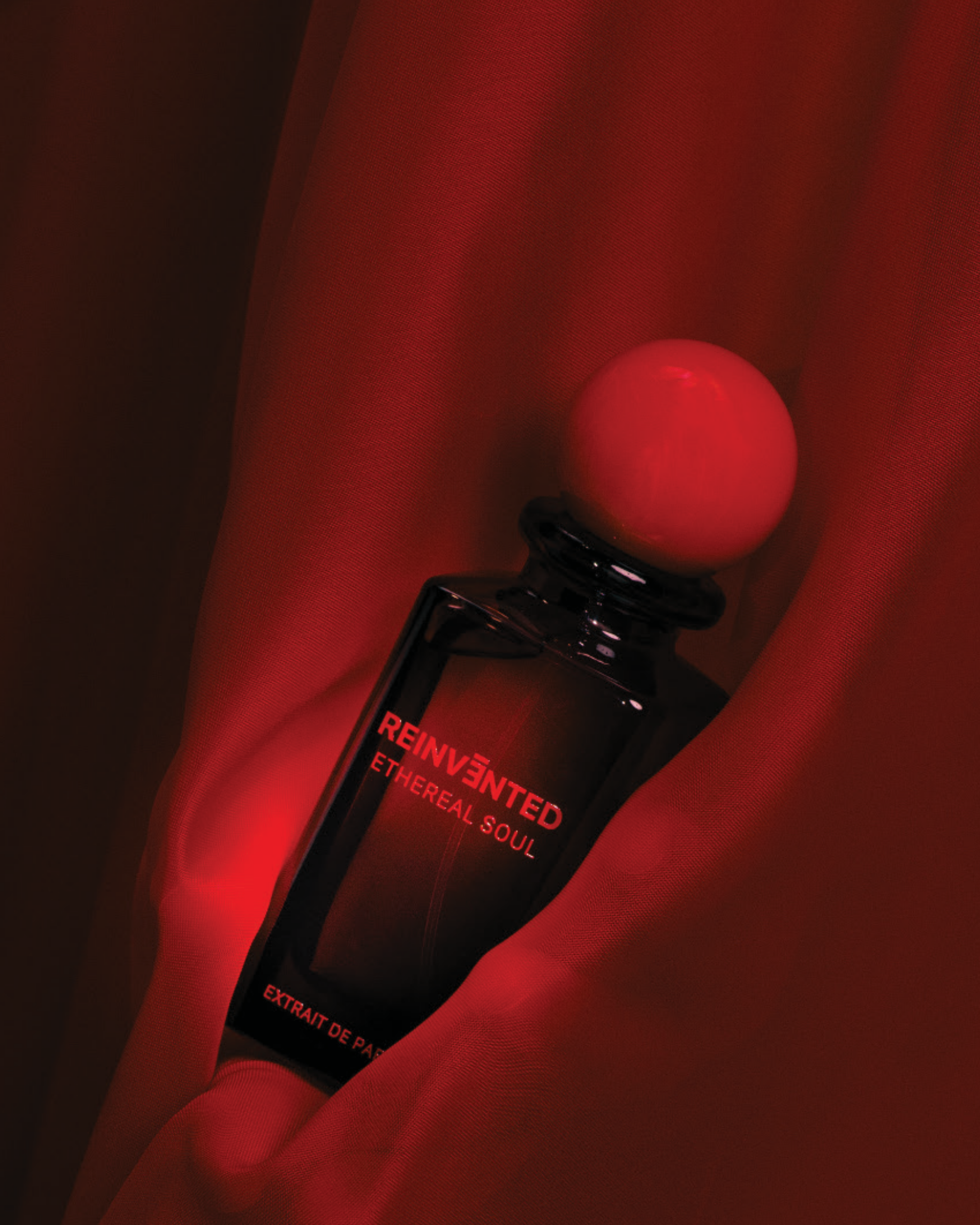 Image of Perfume bottle labeled 'Reinvented Ethereal Soul' on a red fabric background