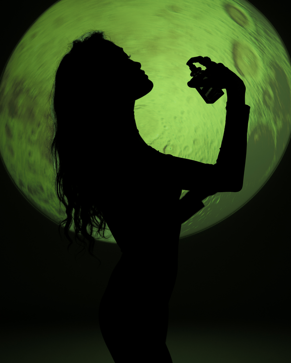 Silhouette of a person holding a spray can against a green moon-like background
