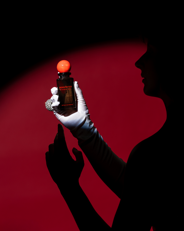 Person holding a bottle with an orange cap against a red background