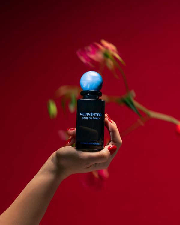 Hand holding a blue light bulb-shaped product against a red background